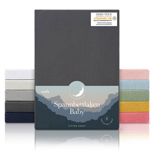 Verpackung von anthrazitfarbenen Spannbettlaken für Babys mit Öko-Tex Standard 100 Siegel präsentiert neben einem Stapel Laken in verschiedenen Farben.