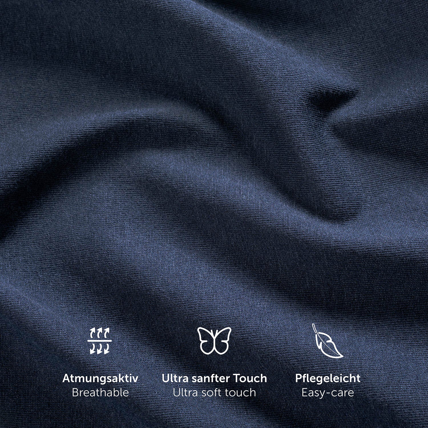Nahaufnahme der Textur eines dunkelblauen Spannbettlakens mit Symbolen für Atmungsaktivität ultra weichen Touch und Pflegeleichtigkeit.