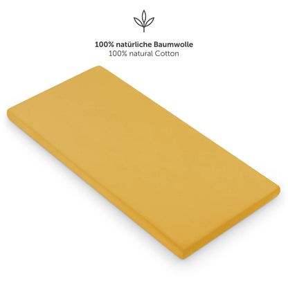 Einzelnes gelbes Spannbettlaken auf einer Matratze mit dem Hinweis auf 100% natürliche Baumwolle