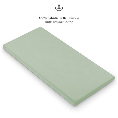 Einzelnes grünes Spannbettlaken auf einer Matratze mit dem Hinweis auf 100% natürliche Baumwolle
