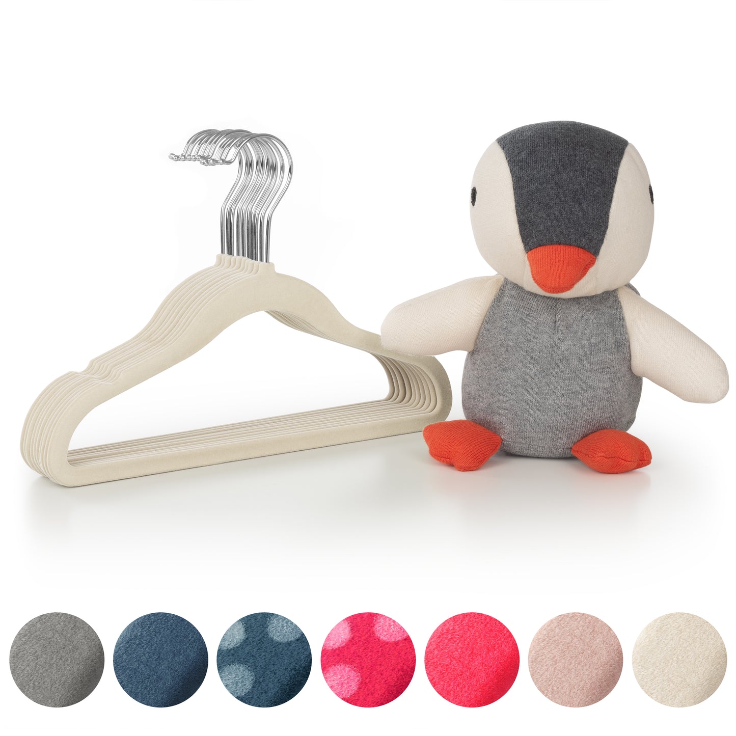 Stofftier Pinguin neben einem Stapel elfenbein Kinderkleiderbügel und Stoffmustern in verschiedenen Farben