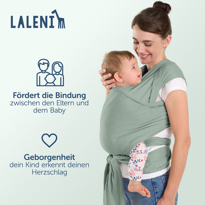 Frau mit Baby in grüner Tragehilfe lächelt sich an Informationen zu Bindung und Geborgenheit werden präsentiert.