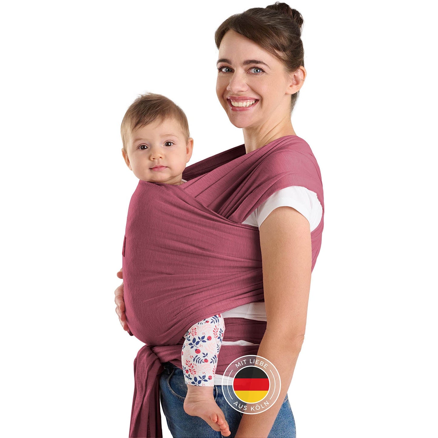 Frau mit Hochsteckfrisur trägt Baby in roter Tragehilfe vor sich beide schauen zur Kamera.