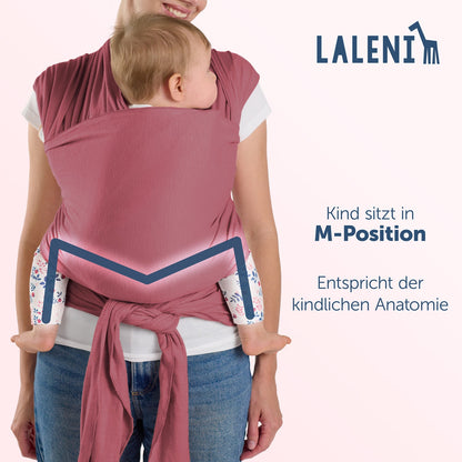 Rückenansicht einer Frau mit Baby in roter Tragehilfe die M-Position und anatomische Korrektheit des Sitzes werden hervorgehoben.